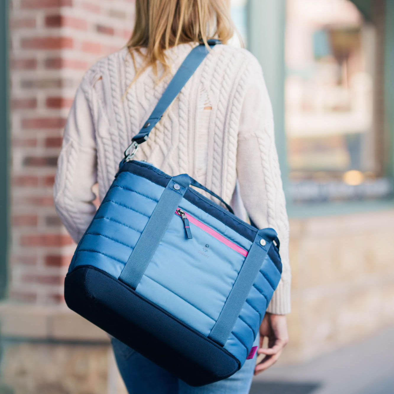 Woman carrying the blue smmt 20 liter tote bag over her shoulder